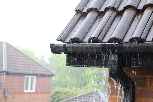 Overflowing gutters during heavy rain demonstrating the importance of well-maintained gutters for water management.