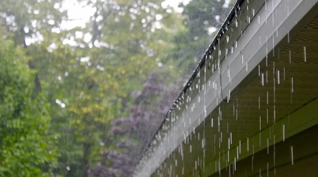 Heavy rainwater flowing off a roof without custom-fit seamless gutters, highlighting the need for proper drainage.