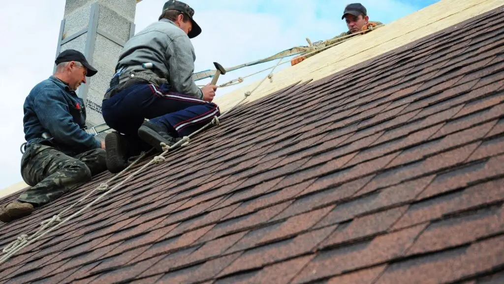 Roofing contractors providing professional roofing services, installing asphalt shingles on a steep residential roof.