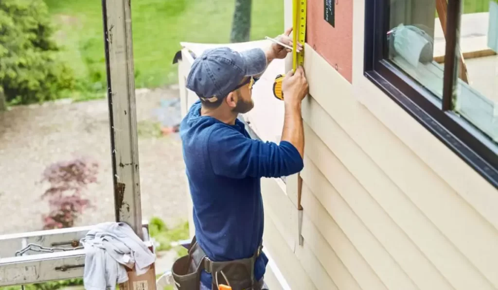 Professional siding contractor measuring wall for precise siding panel installation on residential home in Bolingbrook neighborhood.