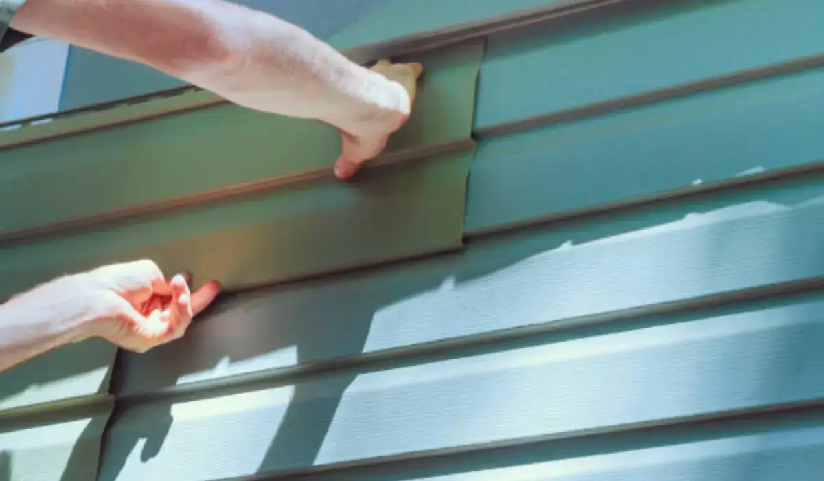 Hands installing siding on a house exterior, demonstrating professional installation techniques for durability and aesthetic appeal.