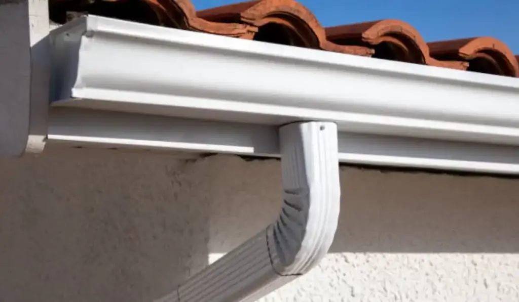 A close-up view of clean and functional gutters with a downspout on a modern home roof, ensuring effective rainwater management.