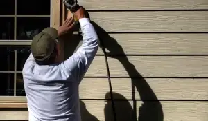 Siding contractor using power tools to install new siding on a residential home in Bolingbrook, Illinois.