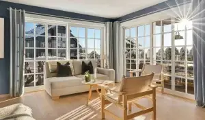 Spacious living room with energy-efficient new windows overlooking a snowy suburban neighborhood, maximizing insulation and natural winter sunlight.