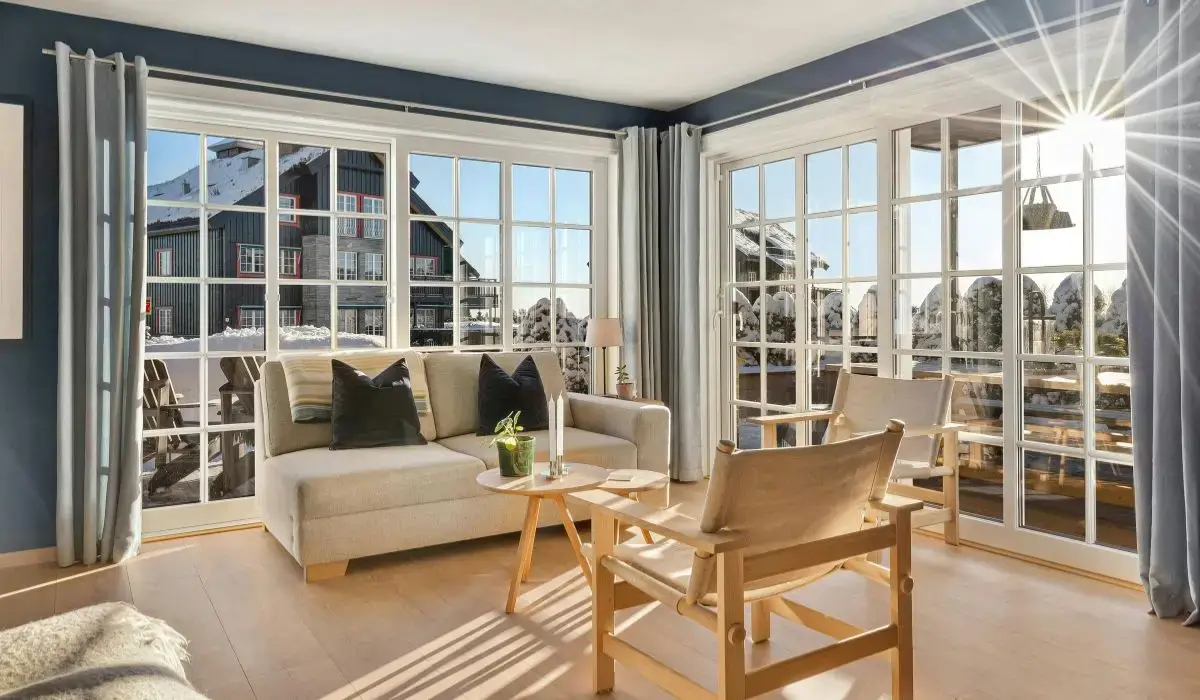 Spacious living room with energy-efficient new windows overlooking a snowy suburban neighborhood, maximizing insulation and natural winter sunlight.