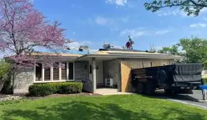 Workers performing roof replacement on a brick home, illustrating Roof Replacement vs Repair decision in progress.