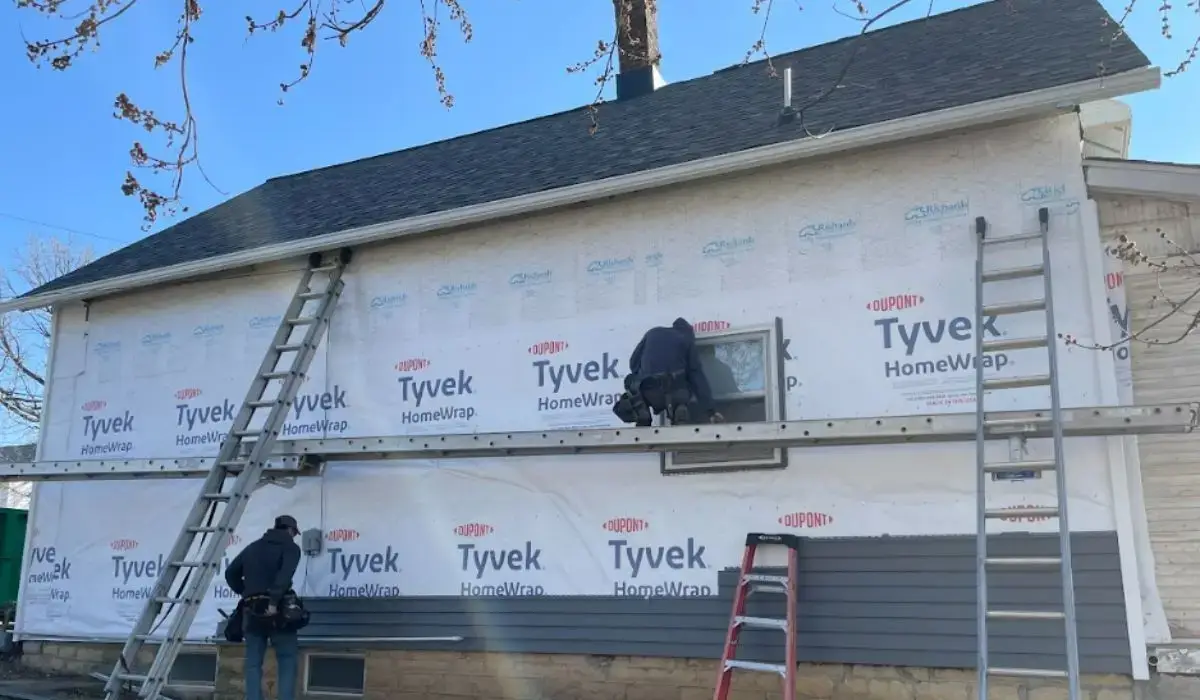 Technicians installing new siding on a Tinley Park home, showing Tyvek wrap and partial siding replacement in progress.