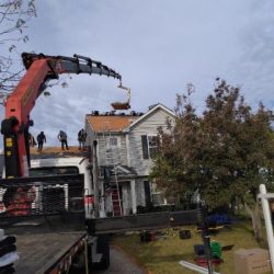 Roof installers in Romeoville, IL working on a residential roof replacement using crane equipment.