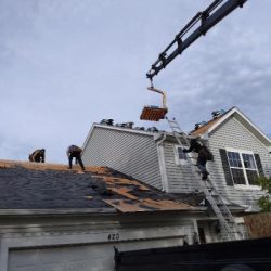 Roofing contractors in Romeoville, IL removing old shingles and preparing for a new roof installation.